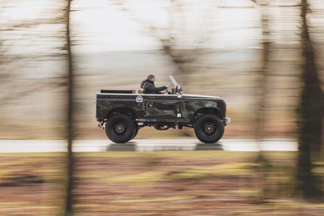 A Series Land Rover in motion on a country road